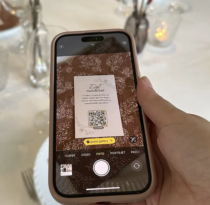 Person holding iPhone showing Guest Gallery app